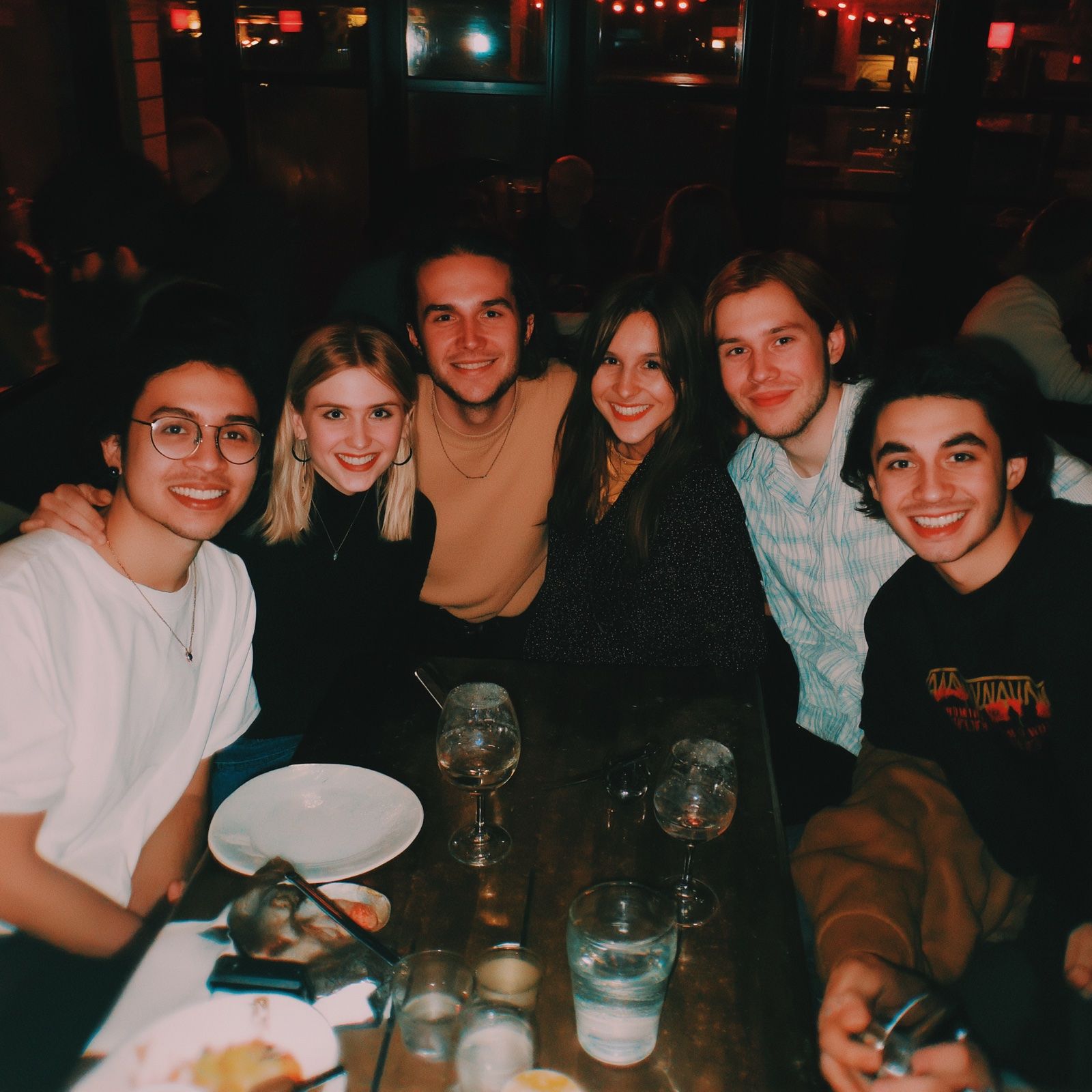 Six friends at a candlelit restaurant table.