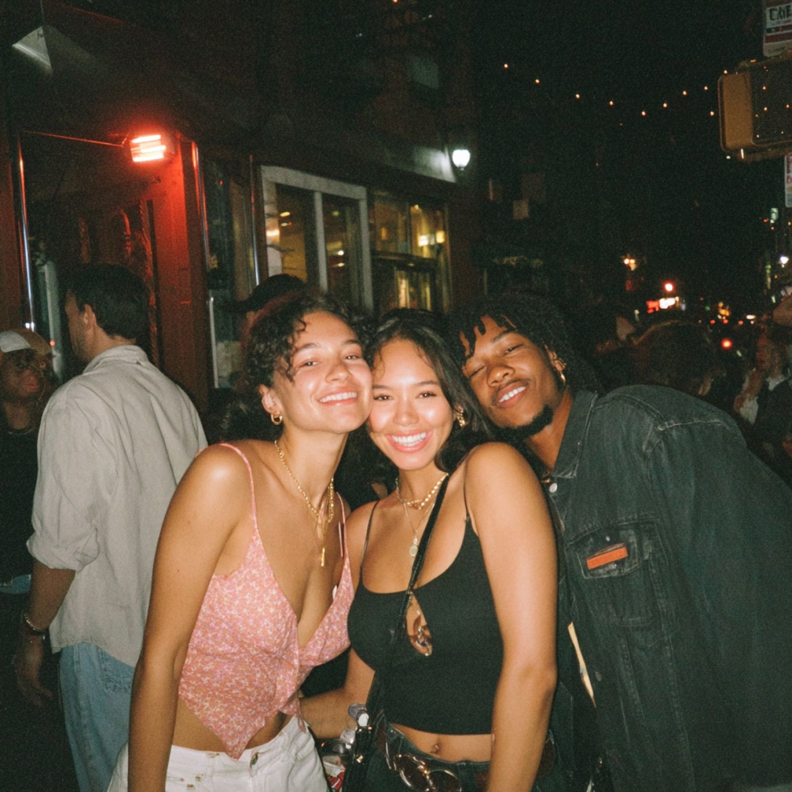 Three friends laughing on a NYC street at night.